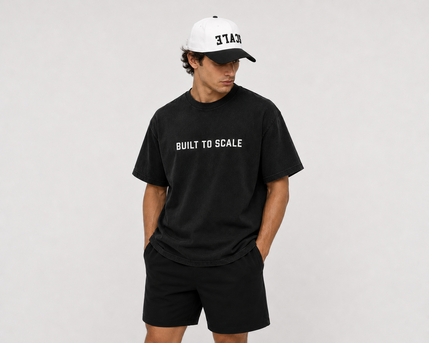 Model wearing the black Built To Scale tee with a white cap